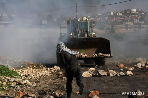 A Palestinian demonstrator throws stones at an Israeli bulldozer during clashes at the weekly protest against the Jewish settlement of Qadomem, near Nablus, West Bank, 28 December 2012. According to Palestinian sources,...