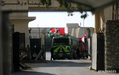 Palestinian men stand near trucks of supplying raw materials of Qatari grant projects in Rafah crossing in the southern Gaza Strip. Egypt allowed access supplying raw materials of Qatari grant projects Through the Rafah...