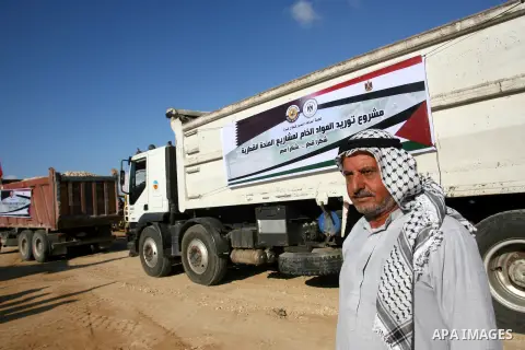 Palestinian men stand near trucks of supplying raw materials of Qatari grant projects in Rafah crossing in the southern Gaza Strip. Egypt allowed access supplying raw materials of Qatari grant projects Through the Rafah...
