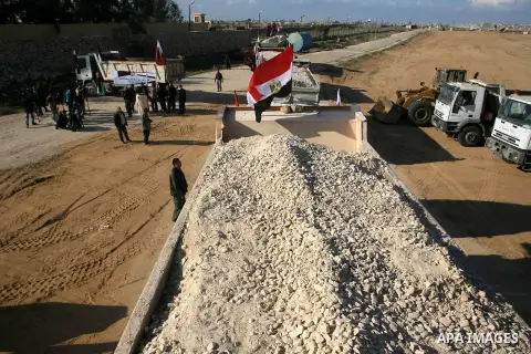 Palestinian men stand near trucks of supplying raw materials of Qatari grant projects in Rafah crossing in the southern Gaza Strip. Egypt allowed access supplying raw materials of Qatari grant projects Through the Rafah...