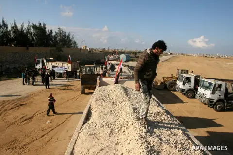 Palestinian men stand near trucks of supplying raw materials of Qatari grant projects in Rafah crossing in the southern Gaza Strip. Egypt allowed access supplying raw materials of Qatari grant projects Through the Rafah...