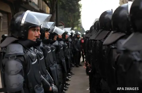 Egyptian riot police stand guard outside the Shura Council, the upper house of parliament where the Constituent Assembly drafted the country's new constitution, as protesters against Egypt's President Mohamed Morsi chant...