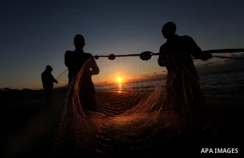 Palestinian fishers prepare to throw their trawl in the sea during sunset on the beach of Gaza city,on December 29, 2012. Photo by Majdi Fathi