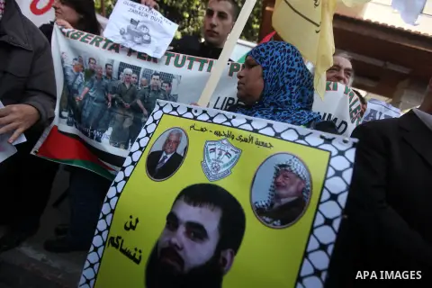 Palestinians hold pictures of prisoners held in the Israeli jails during a rally in Gaza city on December 31, 2012. in solidarity with hunger-striking detainees held by Israel to demand their release from detention witho...