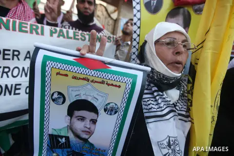 Palestinians hold pictures of prisoners held in the Israeli jails during a rally in Gaza city on December 31, 2012. in solidarity with hunger-striking detainees held by Israel to demand their release from detention witho...