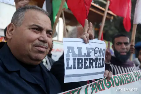 Palestinians and foreign protesters hold pictures of prisoners held in the Israeli jails during a rally in Gaza city on December 31, 2012. in solidarity with hunger-striking detainees held by Israel to demand their relea...