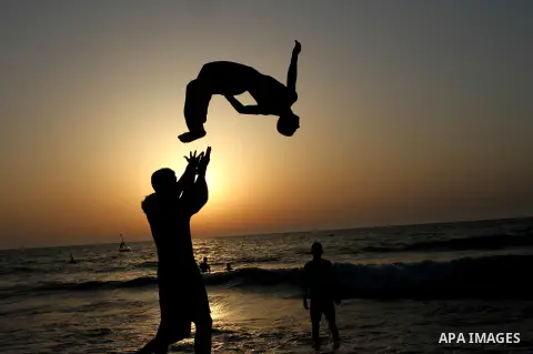 Palestinian boys enjoy playing in the sea at Gaza beach during hot weather in Gaza city, May 03, 2013. Gazans escape to the beach and out from their homes during heat wave and power outages. Photo by Emad Nassar