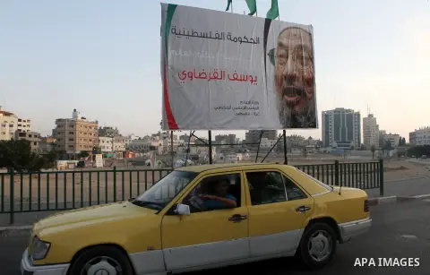 A car is driven past a banner with picture of prominent Muslim scholar Sheikh Yusuf al-Qaradawi, in Gaza city on May 07, 2013. Al-Qaradawi, Qatar-based cleric who is widely-respected through the Muslim world, and undersc...