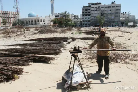 A Palestinian laborer adjusts used steel bars, at a site of an old prison known as al-Saraya that was destroyed by the Isreali airstrikes during the conflict between Israel and Gaza militants, in Gaza city July 4, 2013....
