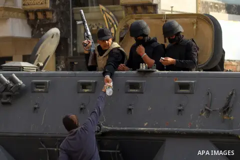 An Egyptian man delivers a water bottle to anti-riot police man during clashes with supporters of deposed Egyptian president Mohamed Morsi in Cairo on January 3, 2014. The protests came after an Islamist alliance backing...