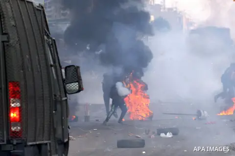 Egyptian anti-riot police forces advance amid smoke and burning objects allegedly set on fire by supporters of the Muslim Brotherhood during clashes in Cairo on January 3, 2014. The protests came after an Islamist allian...