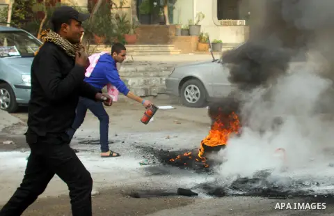 An Egyptian man tries to extinguish a burned tire during clashes between supporters of deposed Egyptian president Mohamed Morsi, police and opponents on January 3, 2014. The protests came after an Islamist alliance backi...