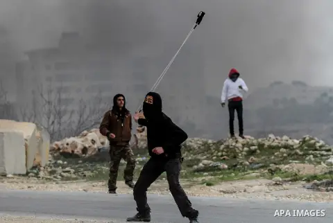 A Palestinian protester throws a stone towards Israeli security forces (unseen) during clashes following a protest of Palestinians against the expansion of the nearby Israeli settlement of Ofra on January 10, 2014 near t...