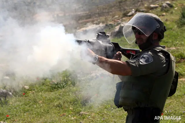 An Israeli soldier fires tear gas canister towards Palestinian youths during clashes following a weekly demonstration against Israel's separation barrier in the West Bank village of Bilin on March 18, 2011. Photo by Issa...