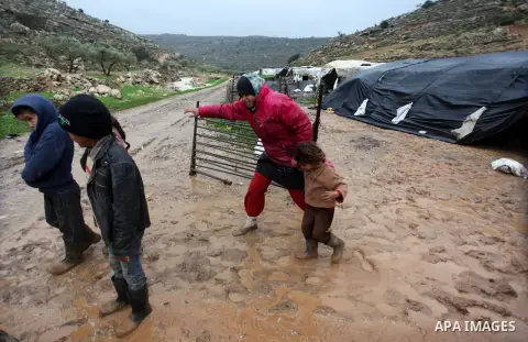 Palestinian Bedouins walk next to their flooded tents in the village of Ein Qiniya near the West Bank city of Ramallah, Jan. 9, 2013. Extreme weather, including torrential rains and heavy winds, killed four people in Isr...