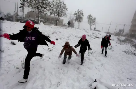 Palestinians play in the snow in the West Bank city of Ramallah January 10, 2013. At least 17 people have died due to a storm in Lebanon, Jordan, Turkey, Israel and the Palestinian territories. Meteorological agencies in...