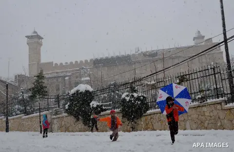 Palestinian kids play with the snow in front of the Ibrahimi Mosque or the Tomb of the Patriarchs on January 10, 2013 in the West Bank city of Hebron. As temperatures plummeted, the bitter winds and rain that have batter...