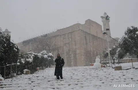 A Jewish settler walks on the snow in front of the Ibrahimi Mosque or the Tomb of the Patriarchs on January 10, 2013 in the West Bank city of Hebron. As temperatures plummeted, the bitter winds and rain that have battere...