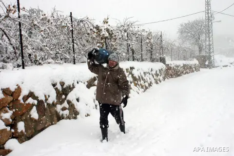 A Palestinian farmer carries a gas canister during snowfall at his farm in the West Bank city of Hebron on January 10, 2013. Abnormal storms, which for four days have blasted the Middle East with rain, snow and hail, lea...