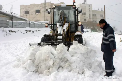 Palestinians try to remove the snow by a bulldozer in the West Bank city of Hebron on January 10, 2013. Abnormal storms, which for four days have blasted the Middle East with rain, snow and hail, leave swathes of Israel...