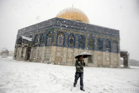A Palestinian man walks in front of the Dome of the Rock mosue as snow falls at the Al-Aqsa mosque compound in the old city of Jerusalem on January 10, 2013. Jerusalem was transformed into a winter wonderland after heavy...