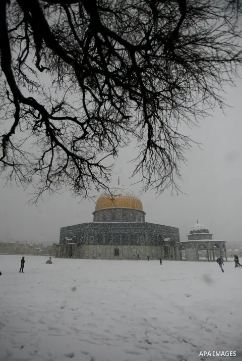 Palestinians walk in front of the Dome of the Rock mosue as snow falls at the Al-Aqsa mosque compound in the old city of Jerusalem on January 10, 2013. Jerusalem was transformed into a winter wonderland after heavy overn...