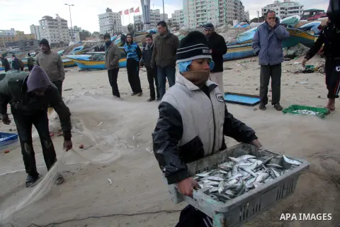 A Palestinian child carries fish after collect during a storm on January 10, 2013 in Gaza City. In Gaza, cold weather and heavy rain flooded several of the tunnels running between the territory and Egypt as in the West B...