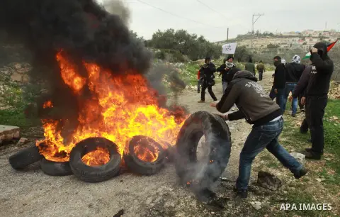 A Palestinian protester burns a tire during clashes with Israeli soldiers following a demonstration against the expropriation of Palestinian land by Israel in the village of Kfar Qaddum, near the occupied West Bank city...