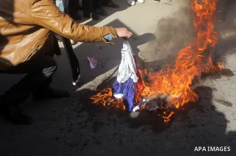 Palestinian protesters burn French flag, during a protest outside the French Cultural Center calling for the release of Lebanese militant Georges Ibrahim Abdallah (portrait L) and Ahmed Saadat, leader PFLP (portrait R),...