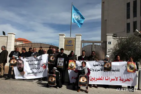 Palestinian protesters hold up banners and portraits of a prisoners in Israel, during a solidarity protest outside the U.N. offices in the West Bank city of Ramallah, on 24 January, 2013 . Demonstrators protested in soli...