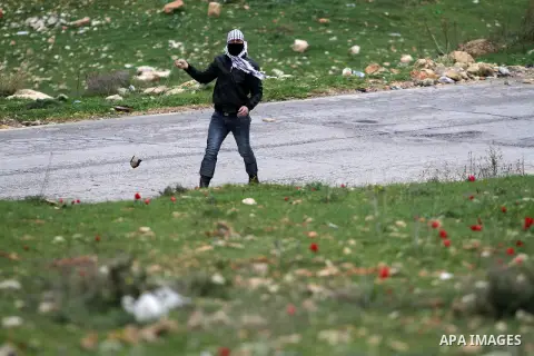 A Palestinian masked protester uses a sling to throw stones at Israeli security officers during clashes at a protest against Jewish settlements, in the West Bank village of Nabi Saleh, near Ramallah Feb. 01, 2013. Photo...