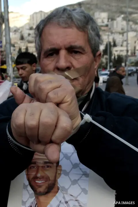 Palestinian protesters hold banners and portraits of prisoners in Israel, during a demonstration in solidarity with hunger-striking Palestinian prisoners held by Israel, demanding their release, in the West Bank city of...