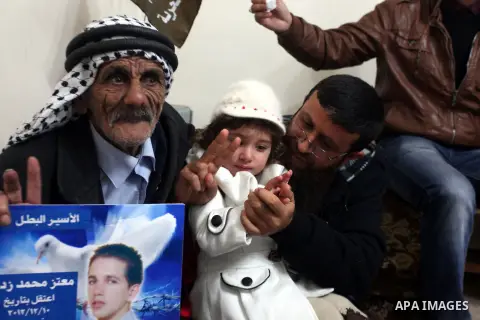 Khader Adnan, a senior member of Islamic Jihad and former Palestinian prisoner who was on hunger strike, plays with a baby girl during a sit-in in the Red Cross headquarter office in solidarity with hunger strike prisone...