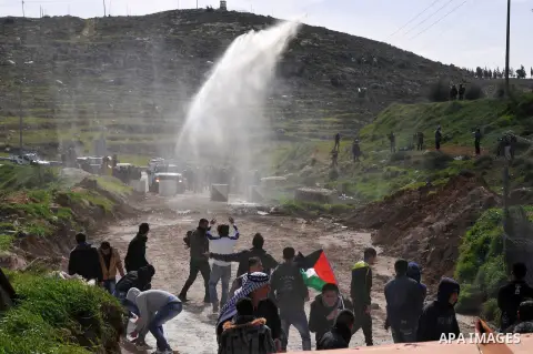 An Israeli truck spray foul smelling water towards Palestinian during a demonstration in protest with the closure of an entrance leading to the West Bank city of Hebron on February 15, 2013. Protesters gathered near Hagg...