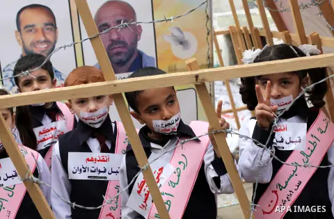 Palestinian children cover their mouth with a sticker during a rally to show solidarity with Palestinian prisoners on hunger strike in Israeli jails, in Gaza City February 19, 2013. The sticker reads:"Yes to hunger, no t...