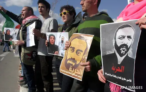 Palestinians carry placards and portraits of prisoners in Israeli jails during a protest in support of prisoners on hunger strike in Israeli prisons, in Jerusalem on February 20, 2013. Some 800 Palestinians serving time...