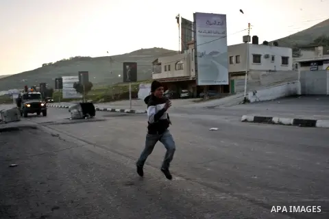 A Palestinian demonstrator runs to seek cover during clashes at Huwwara checkpoint near Nablus, the West Bank, 21 February 2013. According to Palestinian sources, 12 Palestinians were injured during the clashes,and five...