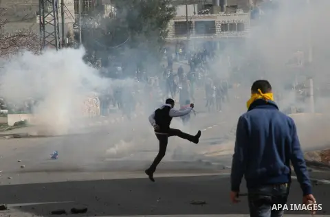 A Palestinian protestor throws stones towards Israeli soldiers during a protest against the death of a Palestinian detainee in an Israeli jail, in the West Bank city of Hebron on February 24, 2013. Palestinian officials...
