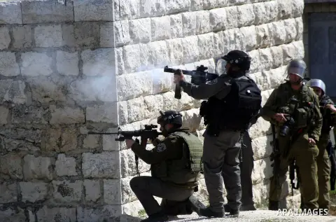 An Israeli soldier fires tear gas at Palestinian protesters during a protest against the death of a Palestinian detainee in an Israeli jail, in the West Bank city of Hebron on February 24, 2013. Palestinian officials on...