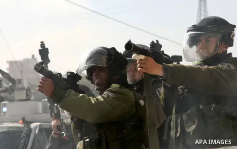An Israeli soldier fires tear gas at Palestinian protesters during a protest against the death of a Palestinian detainee in an Israeli jail, in the West Bank city of Hebron on February 24, 2013. Palestinian officials on...