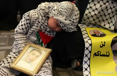 Palestinians hold pictures of prisoners held in the Israeli jails during a protest calling for the release of Palestinian prisoners from Israeli jails in front of the Red cross office in Gaza city, on February 25, 2013....