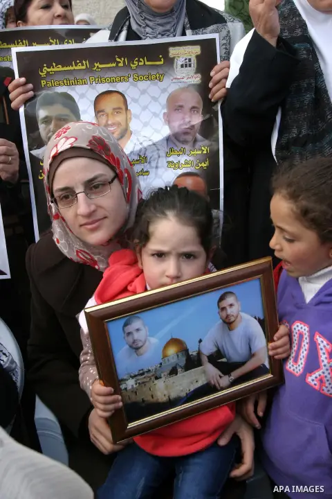 Relatives of Palestinian prisoners jailed in Israeli prisons hold their portraits during a protest in front of Red Cross office in Jerusalem, on 28 February 2013, in support of Palestinian prisoners on hunger strike. Pho...