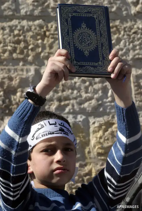 A Palestinian boy carries a copy of the Qur'an, Islam's Holy Book, during a protest against storming of the al-Aqsa mosque compounds by Israeli soldiers and Jewish settlers, in Jerusalem's old city on March 06, 2013. The...