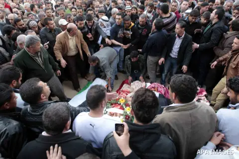 Palestinians mourn over the bodies of victims during a memorial service in the West Bank city of Jenin for Palestinians who were killed on Saturday in a road accident in Jordan, March 17, 2013. Fifteen Palestinian passen...