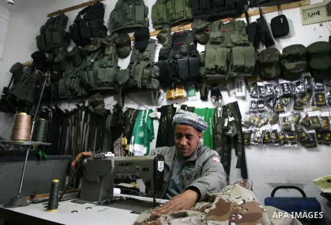 A Palestinian tailor seamstress a military uniform at his workshop in the southern of Gaza strip town of Rafah on March 19, 2013. Egyptian forces seized military-style clothing from a smuggling tunnel near the Gaza borde...