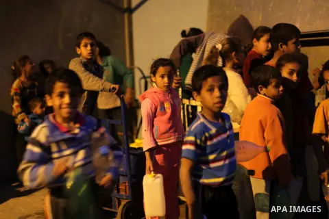 Palestinian boys and girls stand in line holding container as they wait to fill with fresh water from the desalination station in Deir al-Balah refugee camp in the center of the Gaza Strip on March 26, 2013. Photo by Ash...