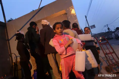 Palestinian boys and girls stand in line holding container as they wait to fill with fresh water from the desalination station in Deir al-Balah refugee camp in the center of the Gaza Strip on March 26, 2013. Photo by Ash...