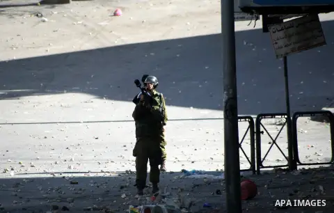 An Israeli soldier fires tear gas at Palestinian protesters during clashes in the West Bank city of Hebron 2 April 2013, after the news of the death of Maysara Abu Hamdiyeh in the Israeli Soroka hospital. Reports state t...