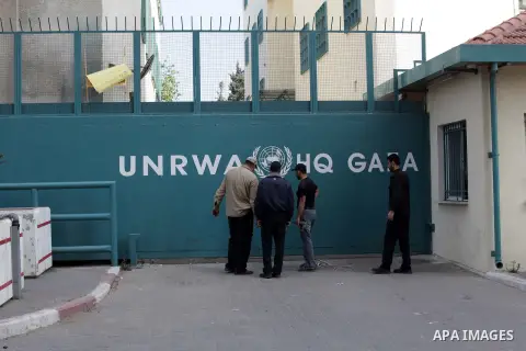Palestinians stand past a United Nations food distribution center in Gaza City, on April 6, 2013. Gaza's Hamas rulers urged the United Nations to reconsider its suspension of food aid for Palestinian refugees, imposed af...