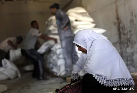 A Palestinian refugee rests next to a flour sack received from United Nations Relief and Works Agency (UNRWA) inside a United Nations food distribution centre in Gaza City April 10, 2013. The main U.N. humanitarian agenc...